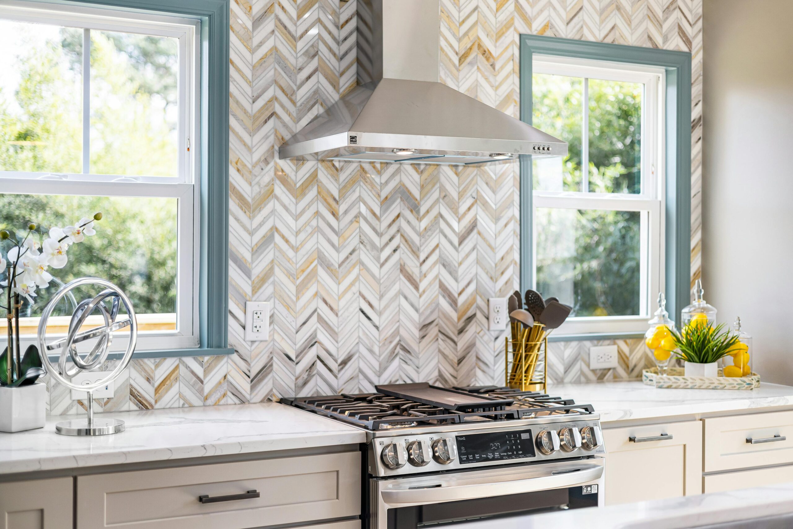 Elegant kitchen featuring modern appliances, chevron backsplash, and natural lighting.